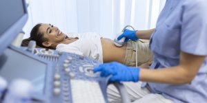 Ultrasound diagnostic of stomach on abdominal to woman in clinic, closeup view. Doctor runs ultrasound sensor over patient's girl tummy and looks at image on screen. Diagnosis of internal organs.